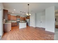 Open kitchen boasts stainless steel appliances, granite countertops, and stylish lighting fixtures at 1412 Afternoon Sun Rd, Matthews, NC 28104