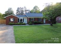 Charming brick home featuring a well-maintained lawn and mature trees, creating a welcoming curb appeal at 1421 Thompson Ave, Charlotte, NC 28216