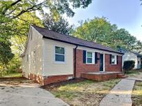 Charming single-story home featuring a brick foundation, light yellow siding, and mature trees in a well-maintained neighborhood at 2214 Grimes St, Charlotte, NC 28206