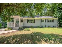 Charming ranch-style home featuring a covered porch, lush green lawn, and mature shade trees at 3331 Eastwood Dr, Charlotte, NC 28205