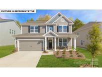 Charming two-story home with gray siding, stone accents, and a well-manicured front yard at 119 Asmodean Ln, Troutman, NC 28166