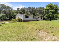 Charming single-story home with a well-maintained lawn and mature trees at 151 Lillyfield Dr, Rockwell, NC 28138