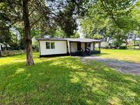 Charming single-story home with a gravel driveway, spacious yard, and lush mature trees offering great curb appeal at 20016 Walter Henderson Rd, Cornelius, NC 28031