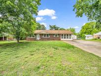 Charming brick home with green shutters, mature trees, and a spacious front yard at 202 College Ave, Shelby, NC 28152
