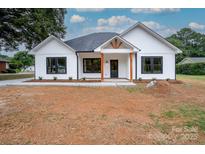 Charming white house with black trim and a covered porch, new construction and modern farmhouse style at 315 W Hoke W St, Landis, NC 28088
