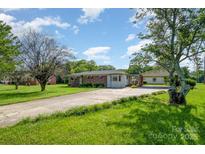 Traditional home with brick accents and a long driveway leading to a detached carport, surrounded by lush greenery at 319 Glenhaven Dr, Charlotte, NC 28214