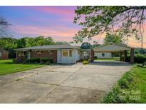 Charming single-story home featuring a brick facade, bay window, and a convenient carport in a serene setting at 319 Glenhaven Dr, Charlotte, NC 28214