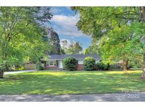 Charming single-story home with mature trees and a well-manicured lawn at 3951 Whitehall Dr, Charlotte, NC 28208