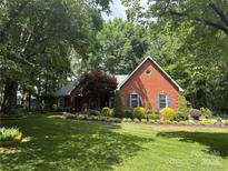 Charming red brick home featuring a well-manicured lawn, mature trees, and colorful landscaping at 5208 Black Oak Ln, Waxhaw, NC 28173