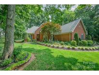 Charming brick home with manicured lawn, lush landscaping, and inviting curb appeal on a sunny day at 5208 Black Oak Ln, Waxhaw, NC 28173