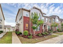 Charming townhome showcasing brick accents, complemented by a well-manicured lawn and lush landscaping at 5391 Orchid Bloom Dr, Fort Mill, SC 29707