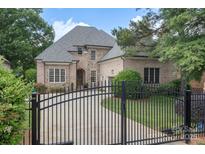 Elegant brick home features a gated entrance, manicured lawn, and a charming blend of stone and brick facade at 6132 Sharon Rd, Charlotte, NC 28210
