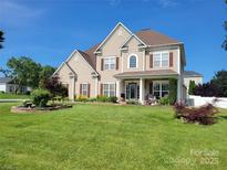 Charming two-story home featuring a well-manicured lawn and lovely front garden beds at 103 Doyle Farm Ln, Mooresville, NC 28115