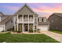 Charming two-story home with inviting front porch, manicured lawn, and attached two-car garage at 1111 Thessallian Ln, Indian Trail, NC 28079