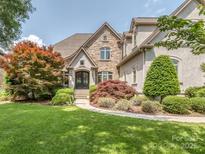Inviting stone-accented home with lush landscaping and a curved walkway leading to the elegant arched front door at 1404 Lookout Cir, Waxhaw, NC 28173