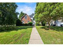 Charming brick home with mature trees and a well-manicured lawn and inviting walkway at 17101 Windy Oaks Ct, Cornelius, NC 28031