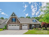 Charming brick and stone home featuring a three-car garage and well-manicured lawn at 1905 Tranquility Blvd, Lancaster, SC 29720