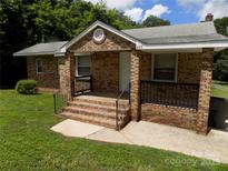 Charming brick home featuring a welcoming front porch and well-maintained landscaping at 209 Barber Rd, Gastonia, NC 28056