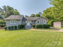 Charming single-story home with manicured lawn, complemented by lush greenery, and a welcoming entrance at 214 Wilcrest Dr, Matthews, NC 28105