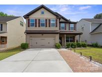 Charming two-story home with a two-car garage, manicured landscaping, and a welcoming brick walkway at 392 Winecoff Woods Nw Dr, Concord, NC 28027