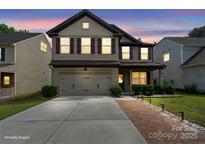Charming two-story home featuring a two-car garage, neutral siding and manicured landscaping, under a beautiful sunset sky at 392 Winecoff Woods Nw Dr, Concord, NC 28027