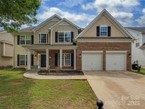 Charming two-story home featuring a brick facade, tan siding, well-kept lawn, and an attached two-car garage at 5607 Fulton Ridge Dr, Indian Trail, NC 28079