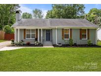 Charming one-story home with a beautifully landscaped front yard and gray brick exterior at 6406 Old Meadow Rd, Charlotte, NC 28227