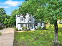Charming two-story home with light blue siding, dark shutters, green lawn, and mature trees at 8514 Timber Crest Cir, Charlotte, NC 28226