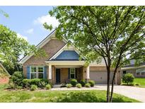 Charming brick home features a manicured lawn, lush landscaping, blue shutters, and inviting front porch at 8840 Mullis Forest Ct, Mint Hill, NC 28227