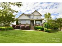 Charming two-story home boasts lush landscaping and a welcoming front porch with rocking chairs at 104 Rockridge Point Dr, Mooresville, NC 28117