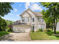 Inviting two-story home features green shutters, a two car garage, and a well-manicured lawn on a sunny day at 12824 Harvest Time Ct, Charlotte, NC 28278