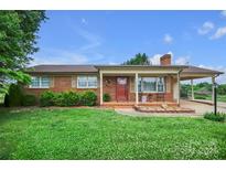Charming brick home featuring a cozy front porch and a well-manicured lawn with mature landscaping at 1609 Troy Rd, Shelby, NC 28150