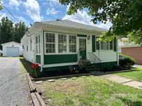 Charming home featuring green and white exterior paint, well-maintained lawn, and a detached one-car garage at 211 Spruce St, Badin, NC 28009