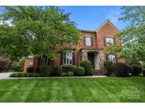 Charming two-story brick home featuring a stone entryway, lush landscaping, and a well-maintained lawn at 3206 Lakehurst Xing, Matthews, NC 28104