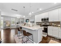 Bright kitchen features white cabinetry, stainless appliances, island with pendant lighting, and adjacent living space at 344 Linestowe Dr, Belmont, NC 28012