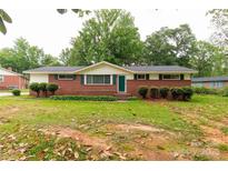 Charming brick home with a well-maintained lawn, mature trees, and a classic design at 405 N Woodland Dr, Lancaster, SC 29720