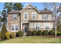 Charming two-story home with stone accents, well-manicured lawn, and lush landscaping at 4095 Harmattan Dr, Denver, NC 28037