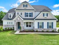 Charming two-story home with blue shutters, stone accents, and a well-manicured lawn at 7160 Sumters Camp Trl, Indian Land, SC 29707