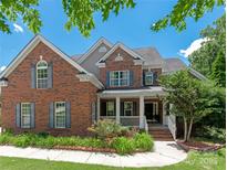 Charming brick two-story home with well-maintained landscaping and a welcoming front porch at 8914 Landsdowne Ave, Harrisburg, NC 28075