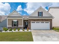 Charming home featuring manicured landscaping, a stone facade, and a two-car garage on a sunny day at 9034 Evercrisp Ln, Charlotte, NC 28215