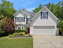 Charming two-story home boasts a well-manicured lawn, red front door, and a two-car garage at 1051 Streamlet Way, Monroe, NC 28110