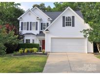 Charming two-story home with a well-manicured lawn, a two-car garage and a striking red front door at 1051 Streamlet Way, Monroe, NC 28110