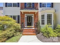 Inviting front entrance features a black door, brick steps, and lush landscaping at 1147 Anduin Falls Dr, Charlotte, NC 28269