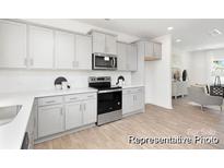 Bright kitchen features white cabinets, stainless steel appliances, white countertops, and wood look floors at 11716 Avocet St # 75, Charlotte, NC 28215