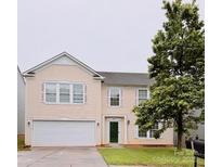 Two-story home with light yellow siding, white trim, attached garage, and mature landscaping at 4521 Palustris Ct, Charlotte, NC 28269