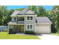 Charming two-story home with a well-manicured lawn, beautiful plants, gray siding, and a welcoming yellow front door at 8701 W Dixie Dr, Charlotte, NC 28278