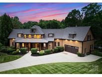 Stunning two-story home featuring a manicured lawn, mature trees, and a welcoming front porch at sunset at 116 Creeky Hollow Dr, Mooresville, NC 28117