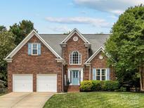 Beautiful brick home with a two-car garage, blue shutters, a well-manicured lawn, and a blue front door at 15313 Moate Ct, Huntersville, NC 28078