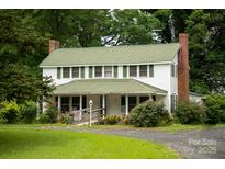 Charming two-story home with a green roof, brick chimney, and a welcoming front porch at 1612 Forum Ln, Iron Station, NC 28080