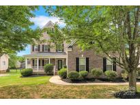 Charming two-story brick home featuring a welcoming front porch and well-manicured landscaping at 6718 Heritage Orchard Way, Huntersville, NC 28078